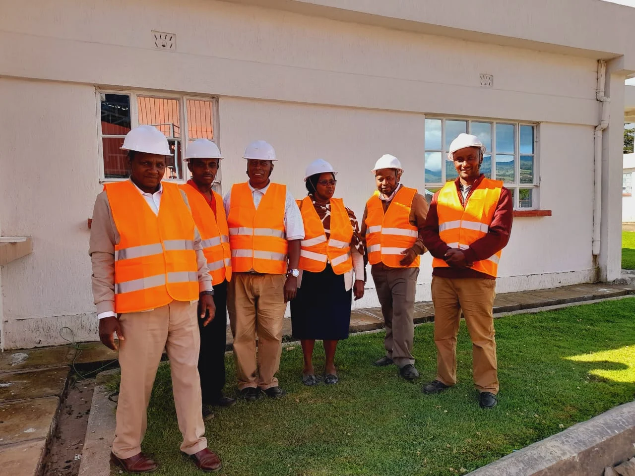Six Ranges Sugar team members in hard hats and high-visibility vests outside a factory building